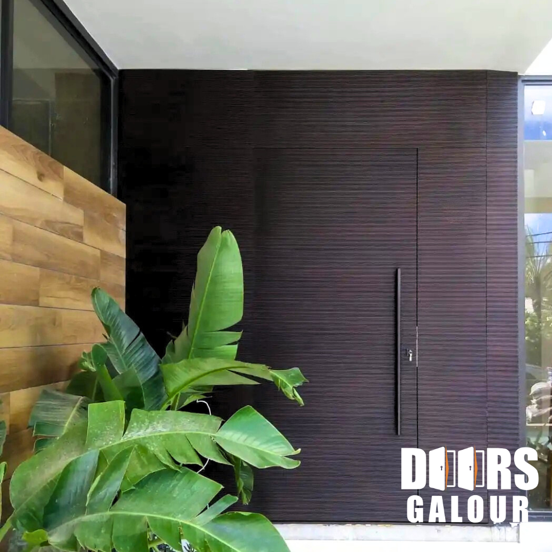 Dark brown textured front door with long handle, beside greenery and wood paneling.