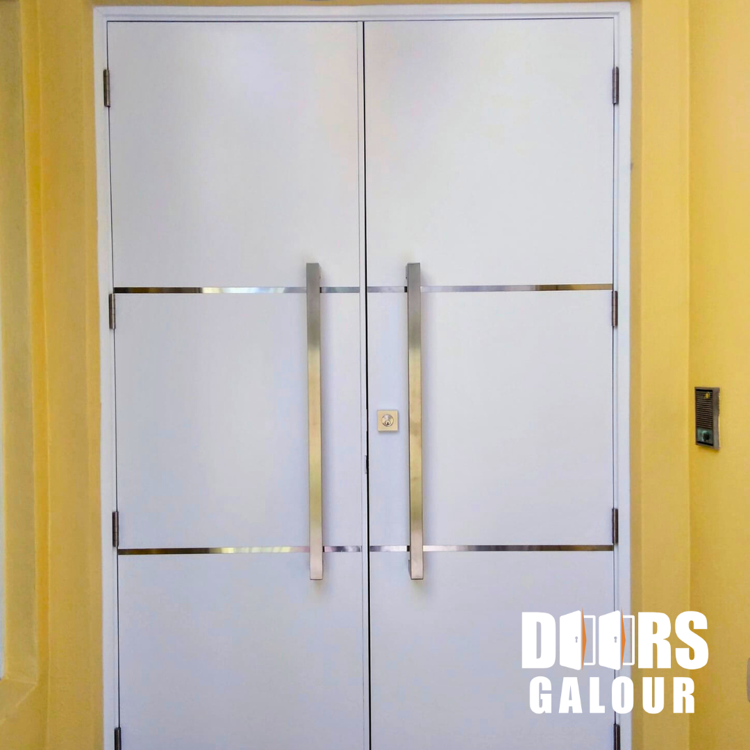 White double doors with silver handles and trim against yellow wall.