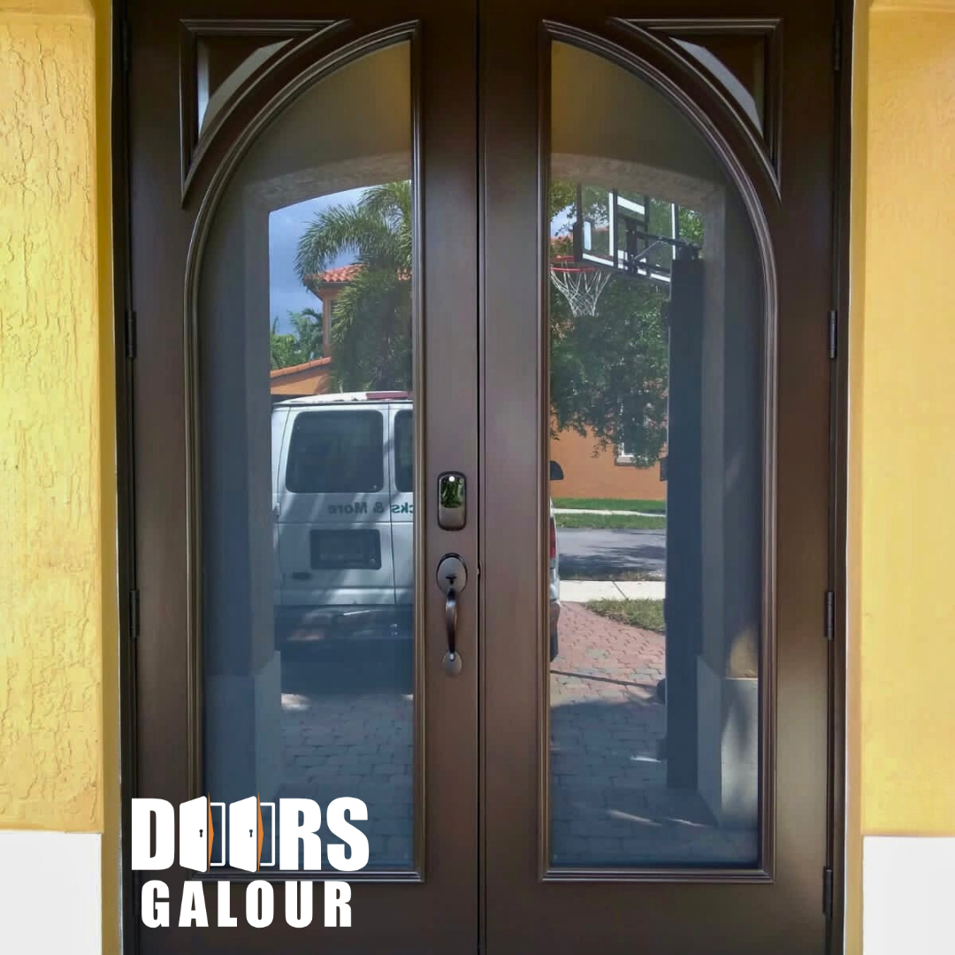 Double brown entry doors with arched glass panels; a white van and a basketball hoop are reflected.