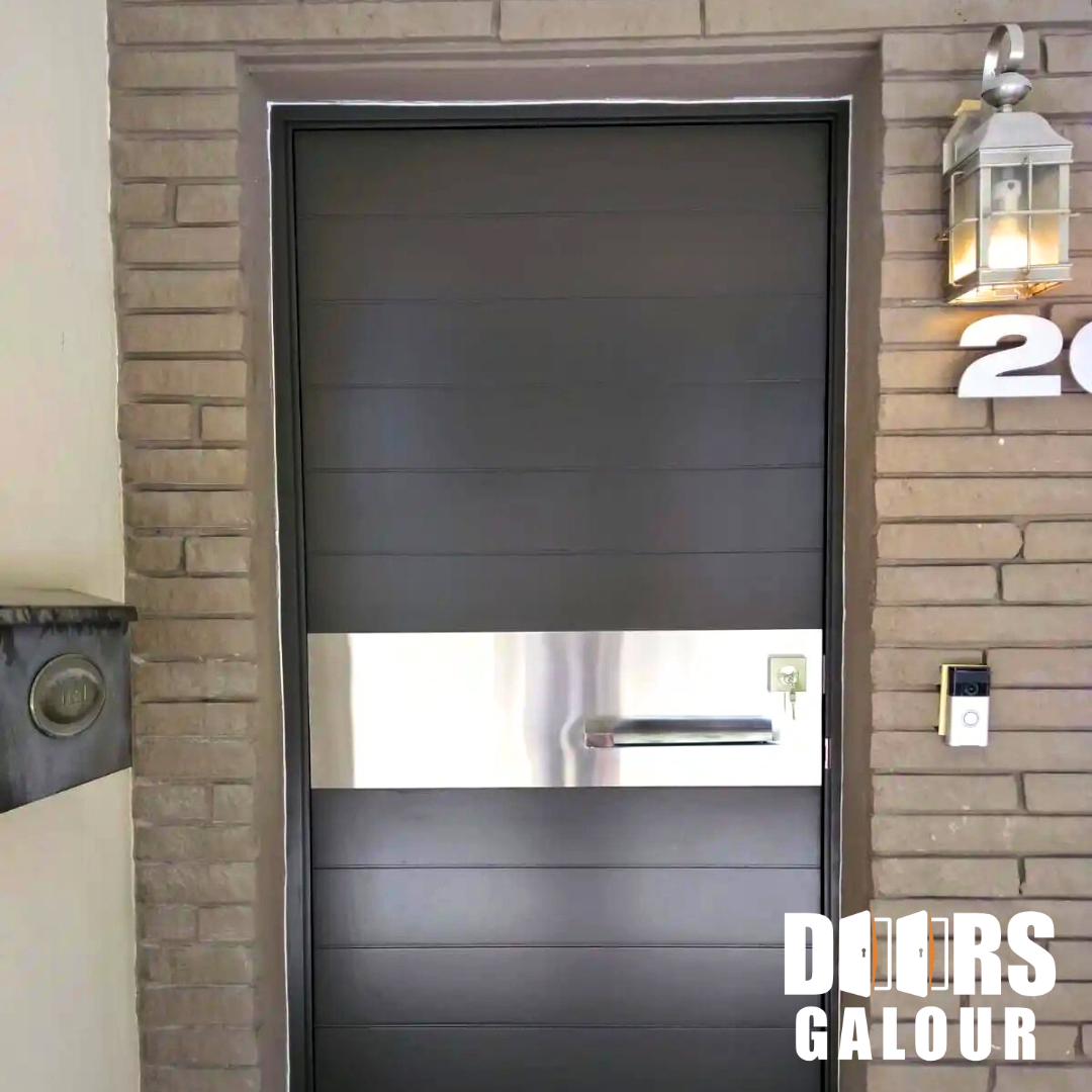 Black door with horizontal lines and a silver mail slot. Set in a brick frame, with a light and address numbers.