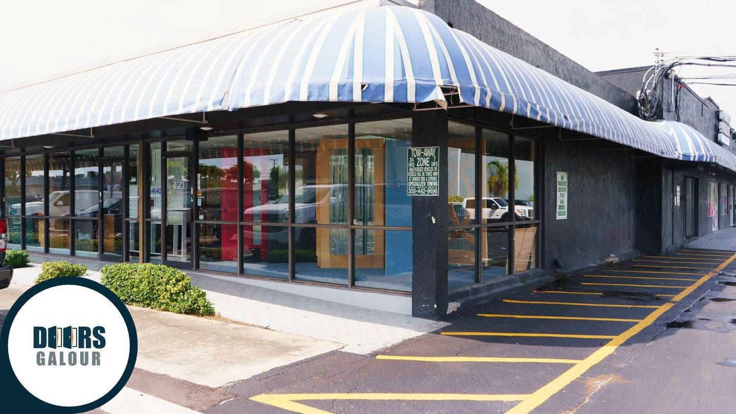 Doors Galour building with a blue awning and a parking lot in front of it.
