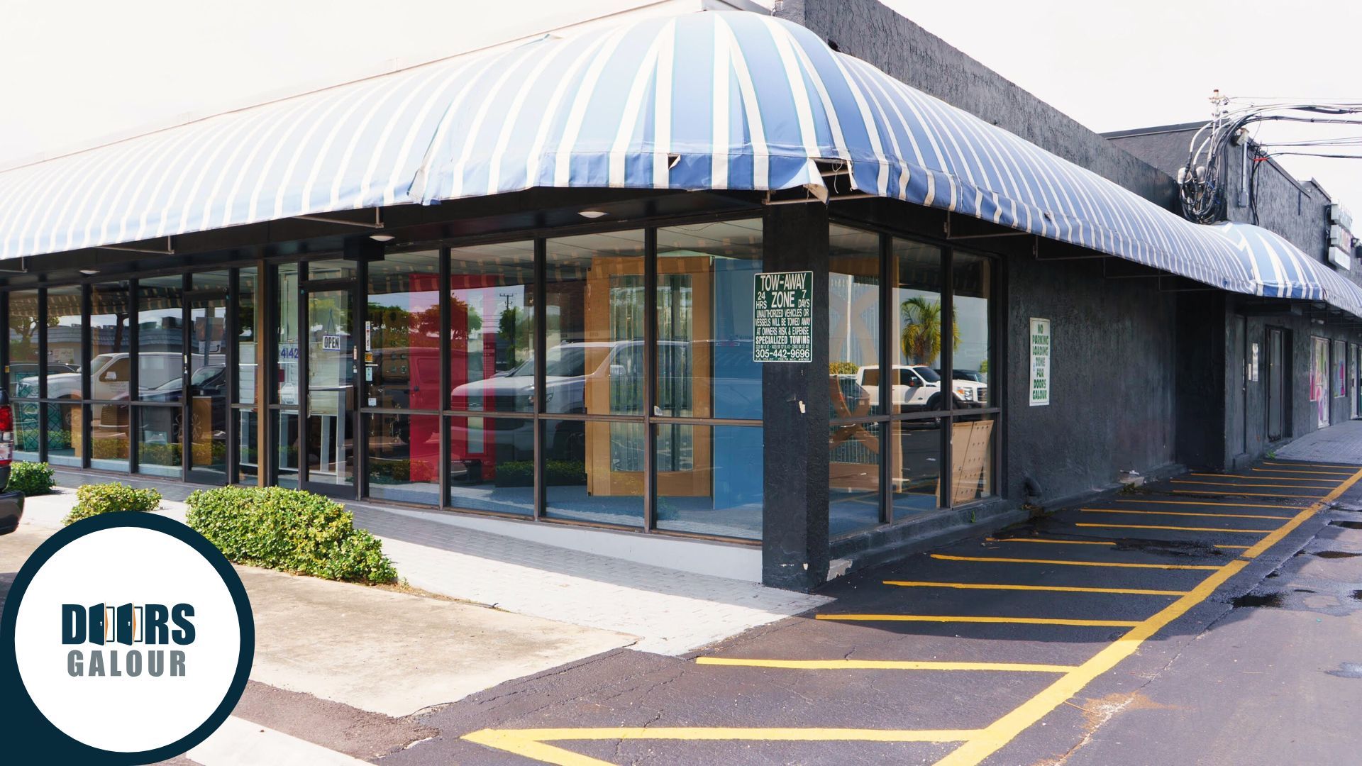 Storefront with blue and white awning, large windows, and "DOORS CALOUR" logo.