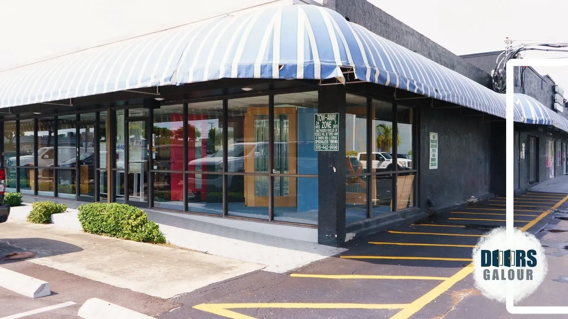 Doors Galour building with a blue awning and a parking lot in front of it.