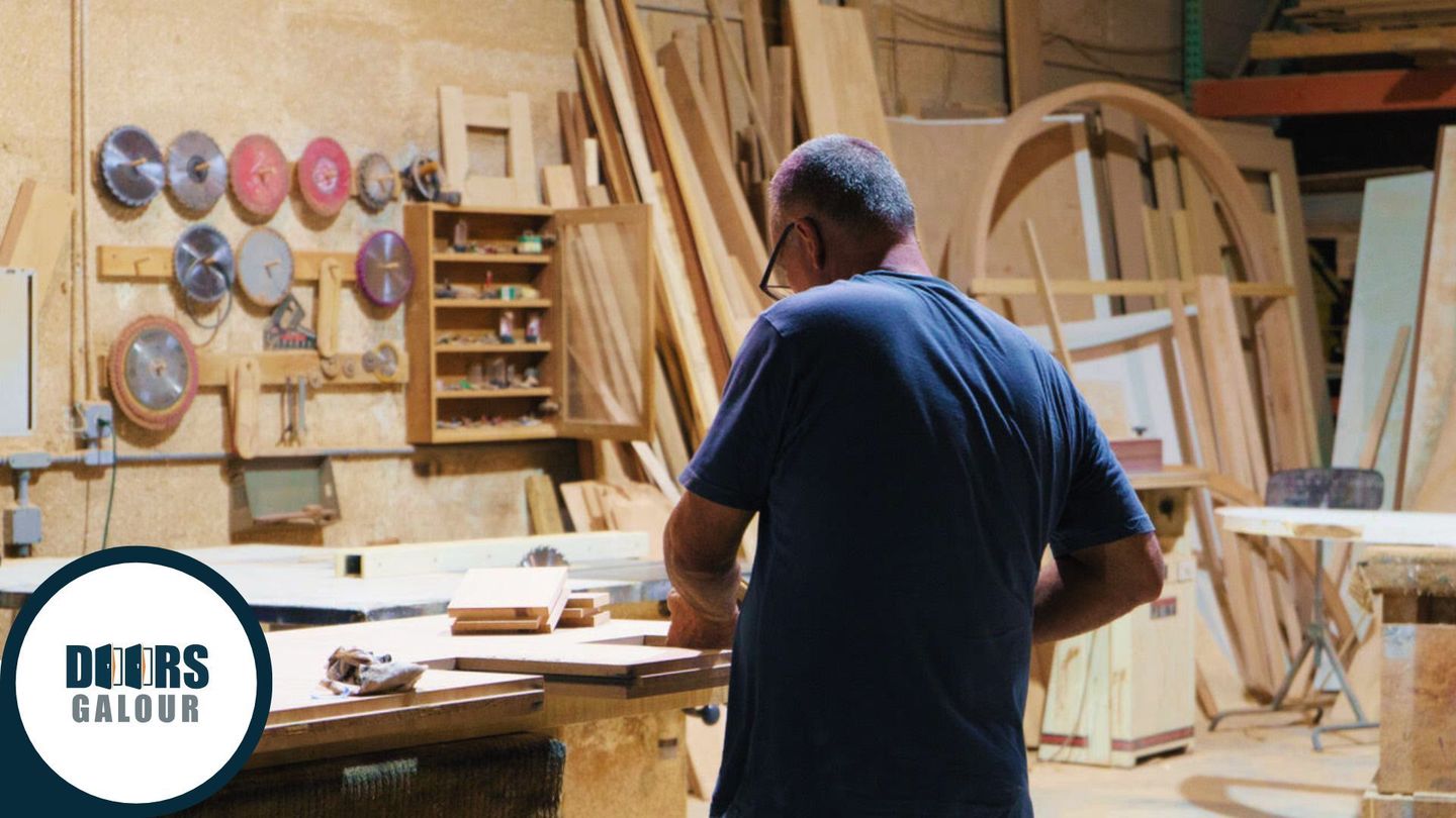 A man in a blue shirt is standing in a woodworking shop.