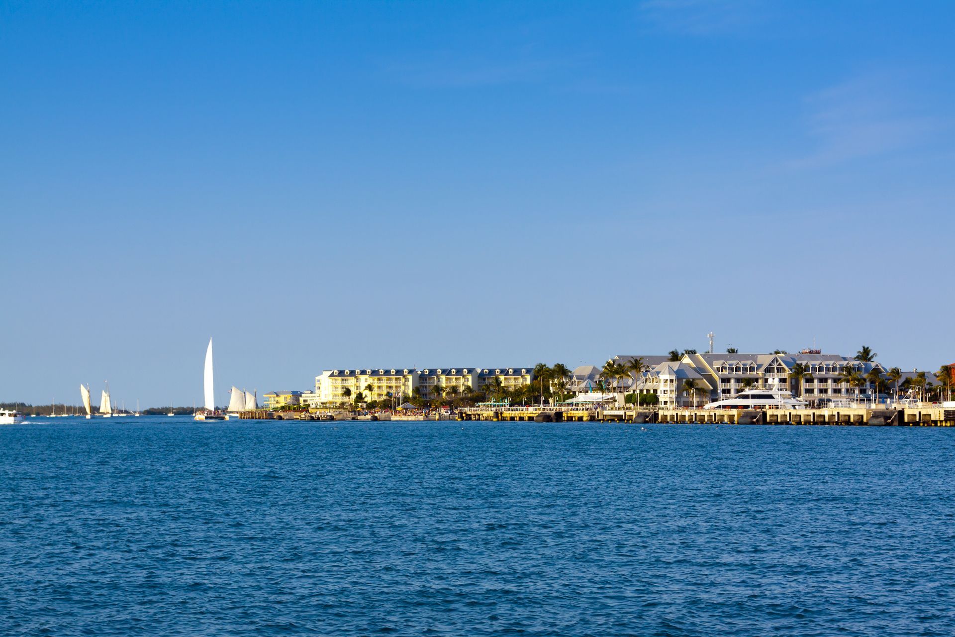 Coastal view of Key West, Florida with buildings, water, boats, and a clear blue sky.
