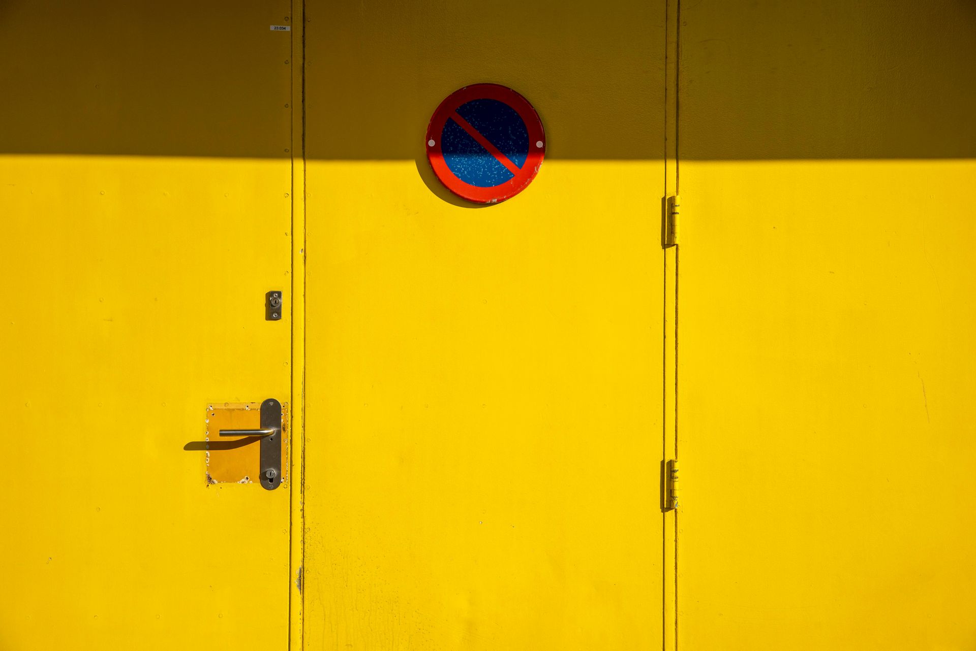 Yellow door with a no-parking sign.