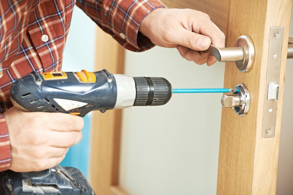 A Man Is Using A Drill To Fix A Door Handle — Illawarra Fasteners Pty Ltd In Unanderra, NSW