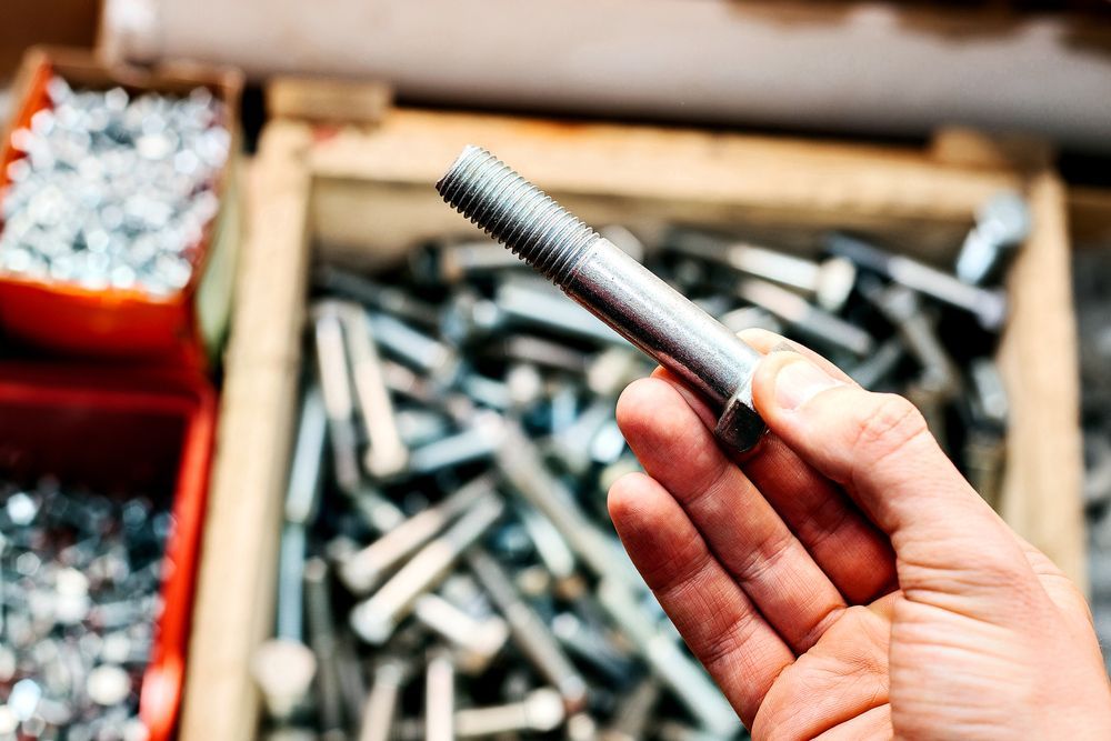 A Person Is Holding A Bolt In Their Hand — Illawarra Fasteners Pty Ltd In Unanderra, NSW