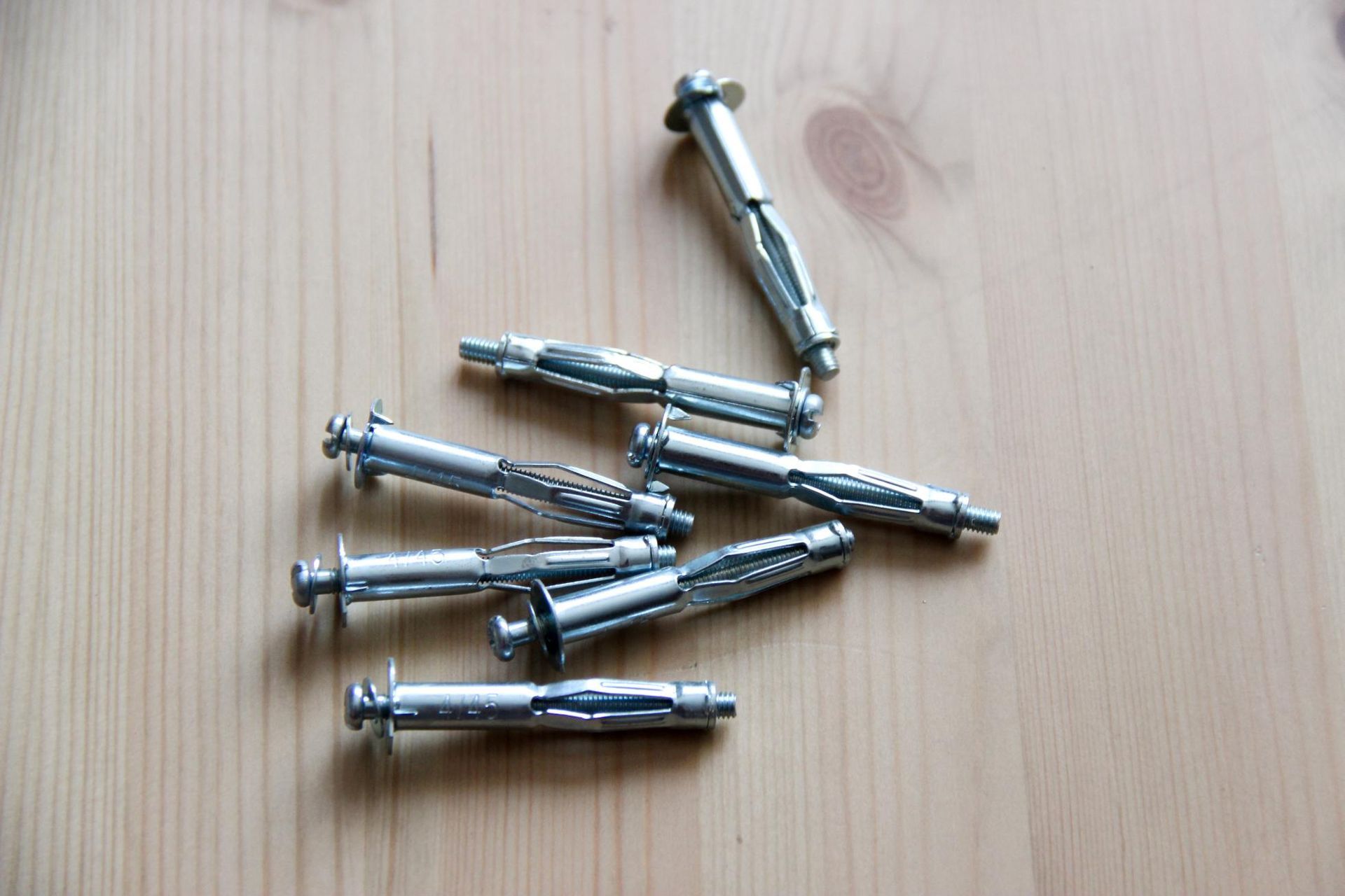 A Bunch Of Metal Screws Are Laying On A Wooden Table — Illawarra Fasteners Pty Ltd In Unanderra, NSW
