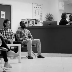 Une photo en noir et blanc de personnes assises dans une salle d'attente