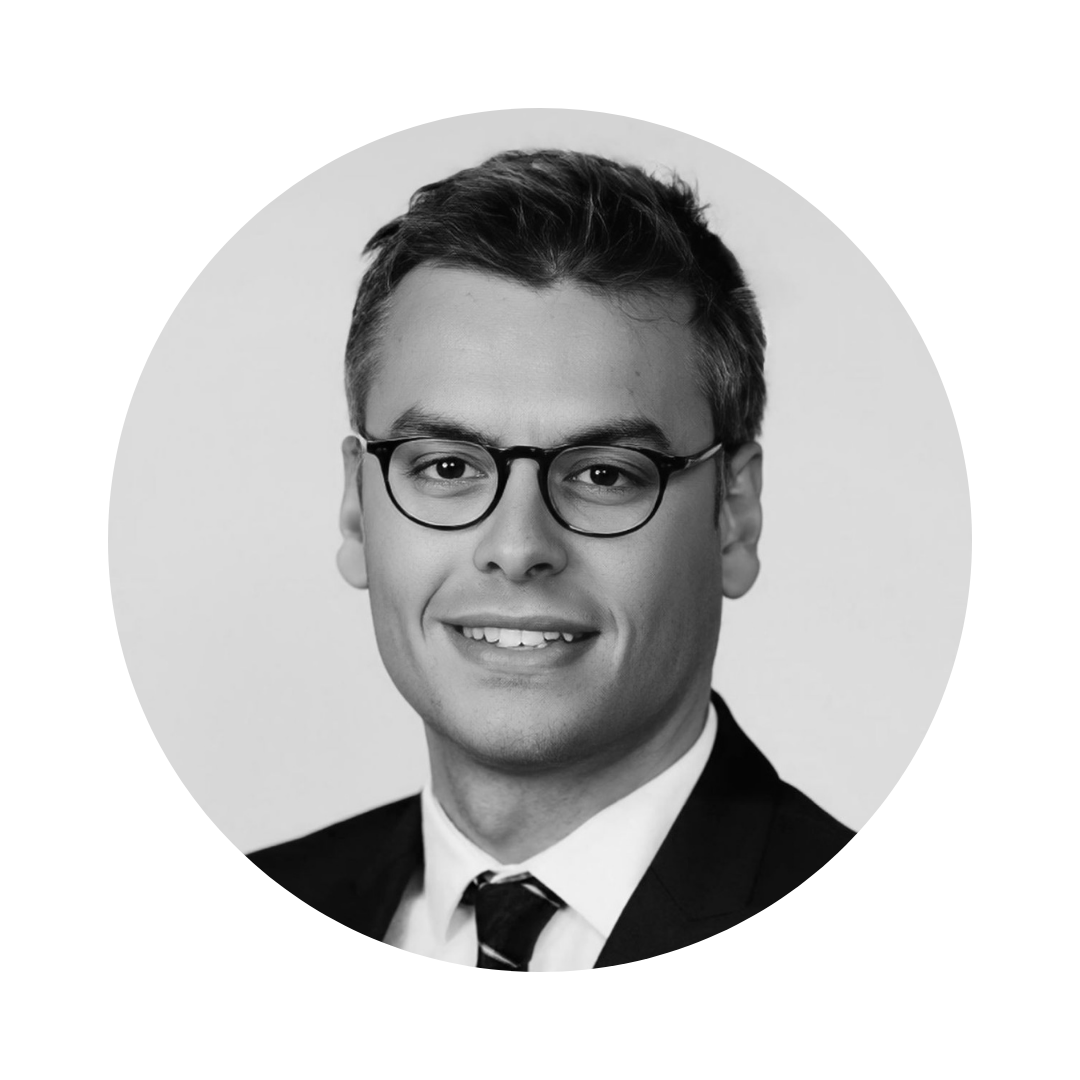 Photo en noir et blanc d'un homme portant des lunettes et un costume.