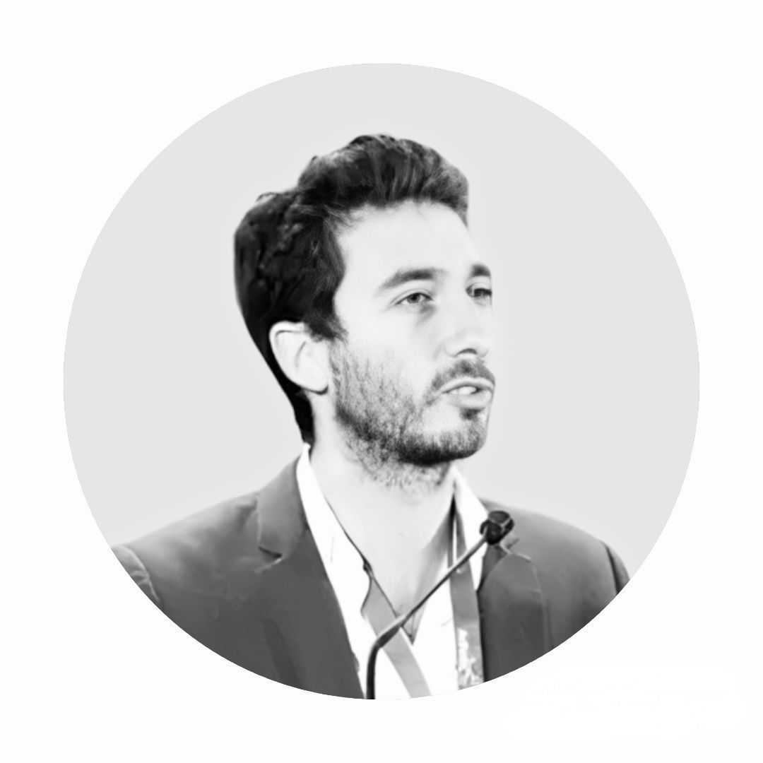 Un homme en costume se tient devant un micro.