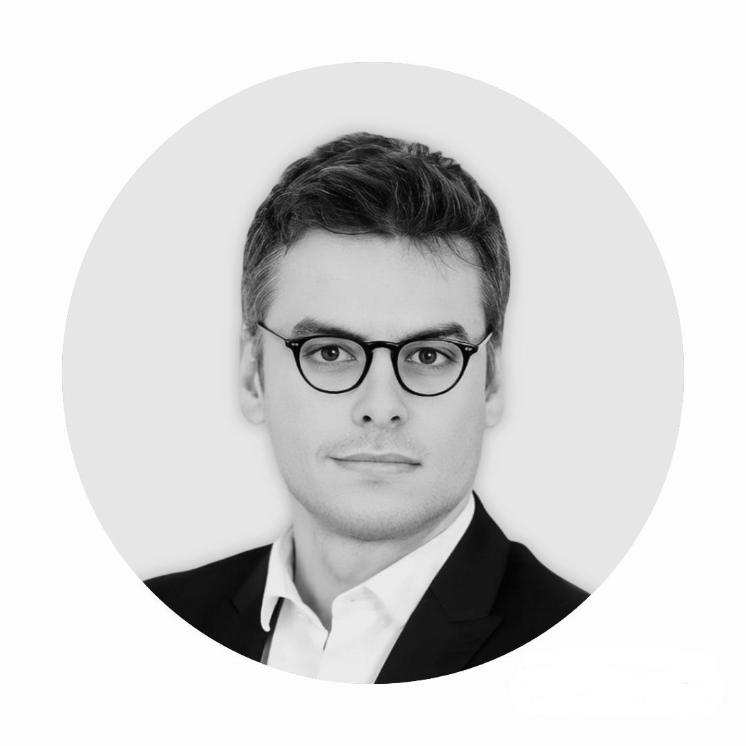 Photo en noir et blanc d'un homme portant des lunettes et un costume.