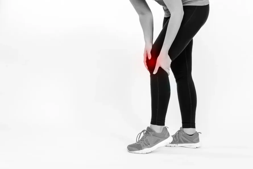 Une femme se tient le genou de douleur.
