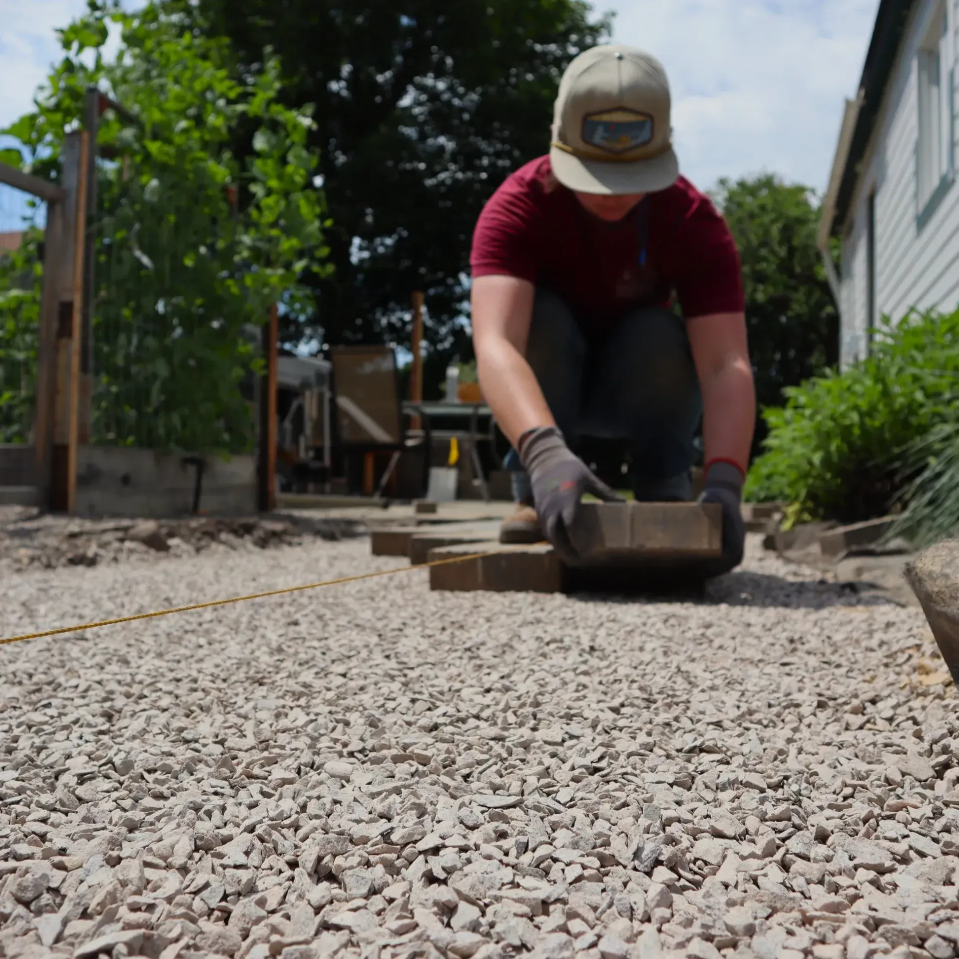 A man wearing a hat and gloves is working on gravel