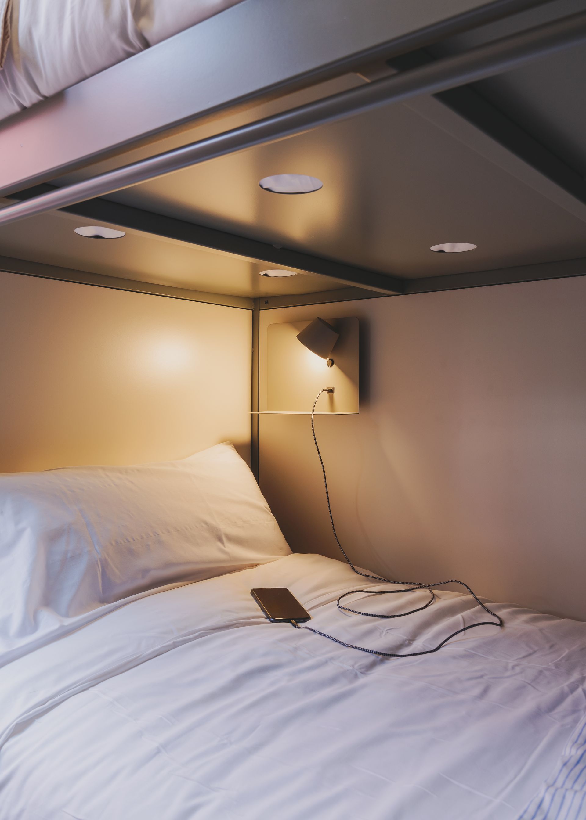 A bed with white sheets and a cell phone on it