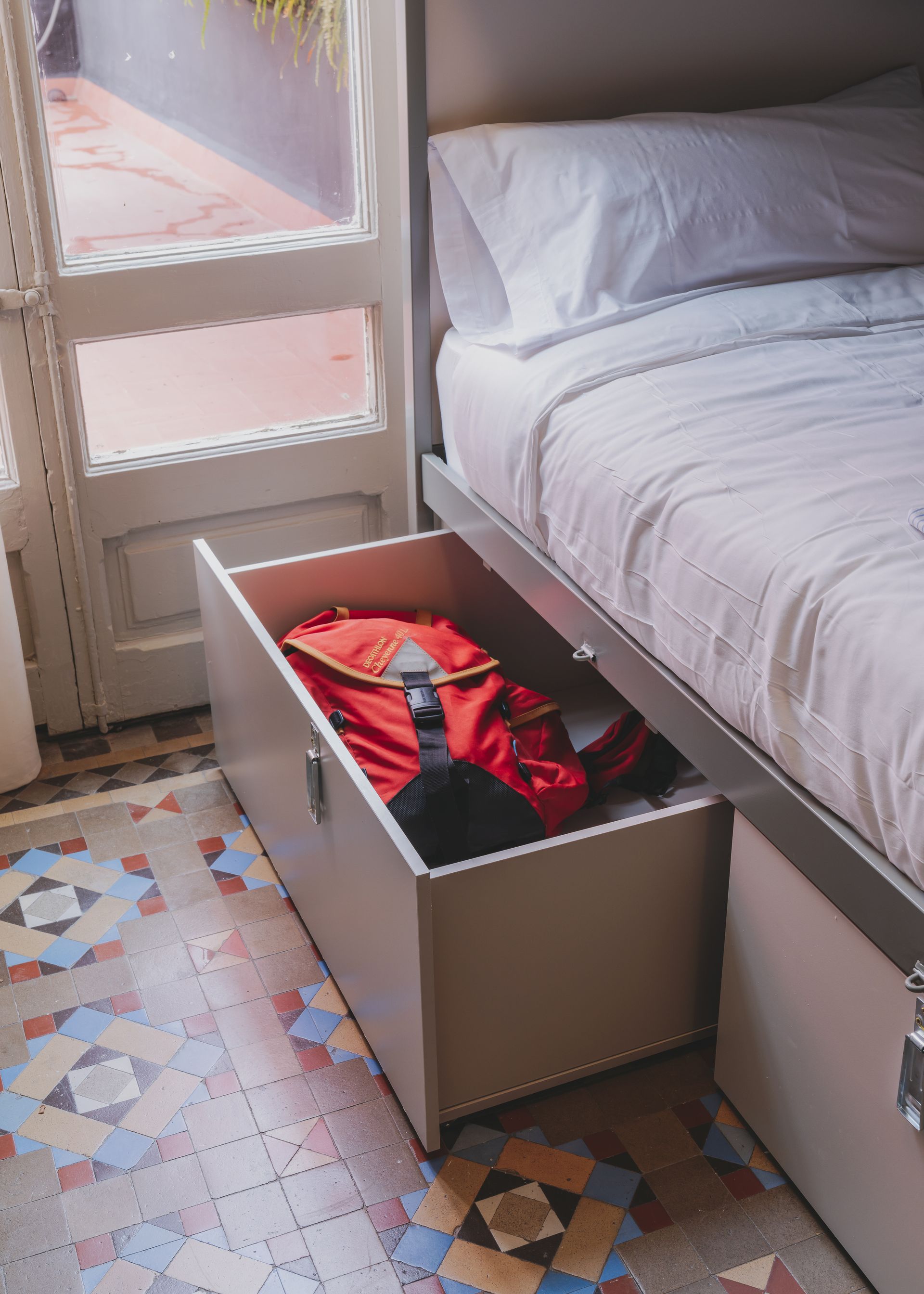A bed with a drawer underneath it filled with clothes.