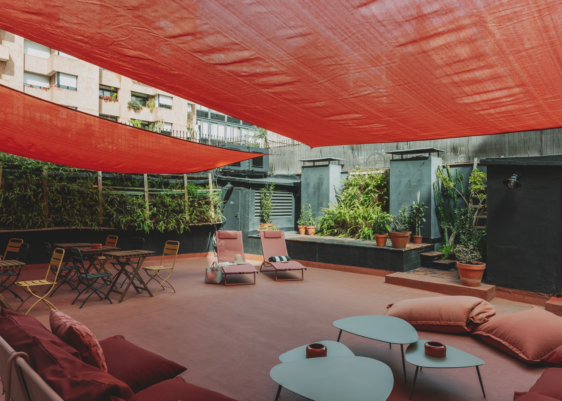 A patio with chairs and tables under a red umbrella