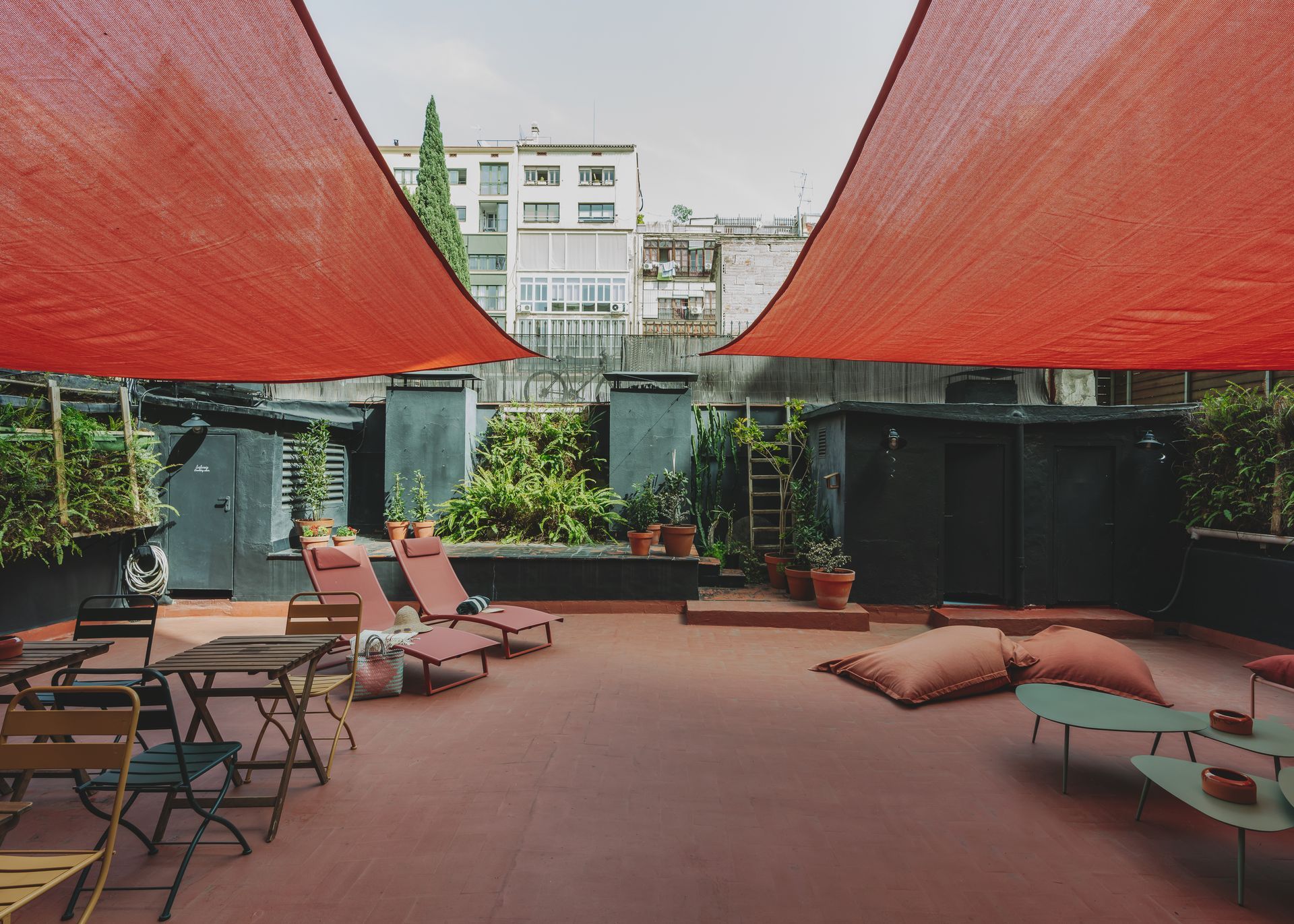 A patio with tables and chairs under red umbrellas