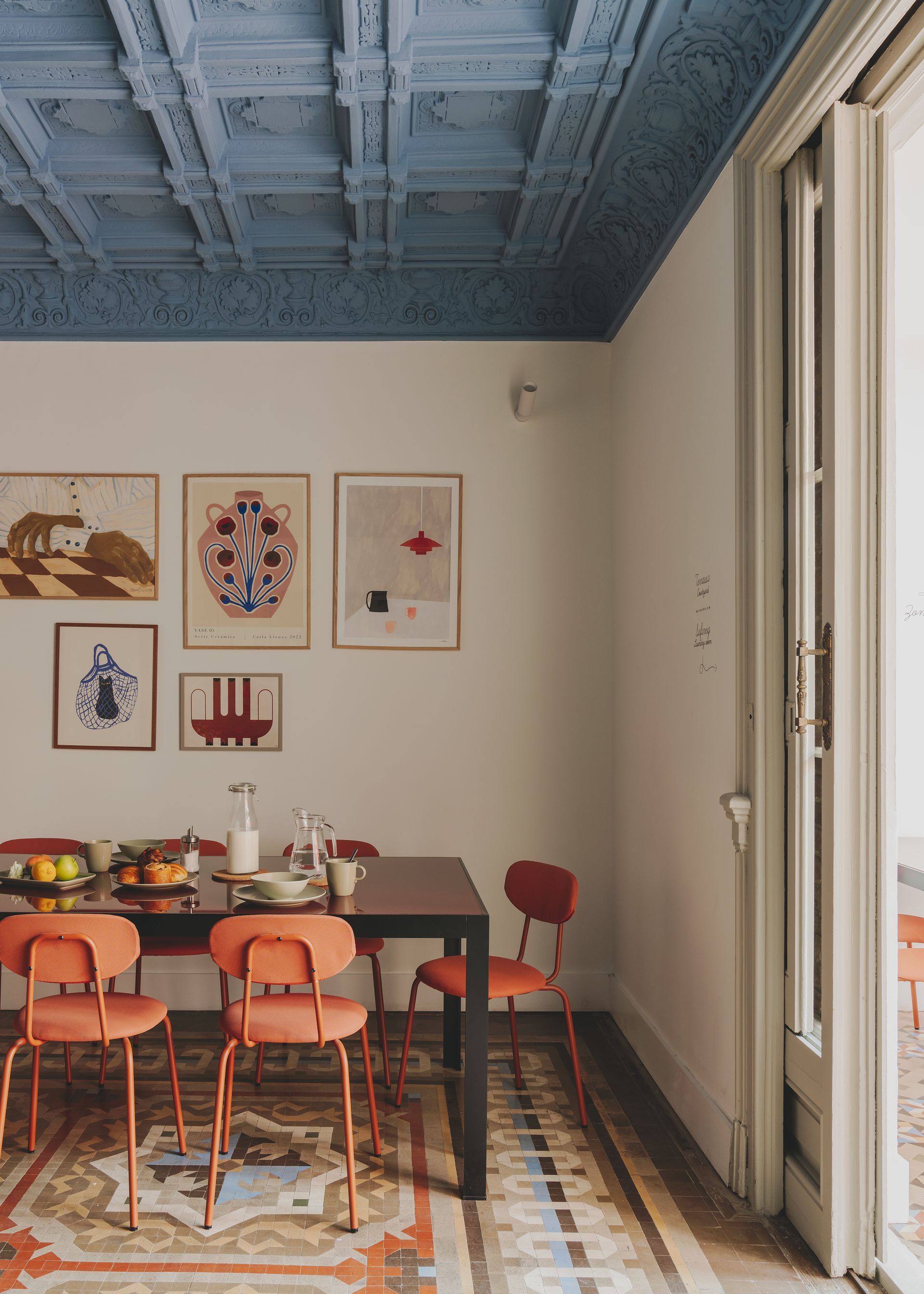A dining room with a table and chairs and a blue ceiling.