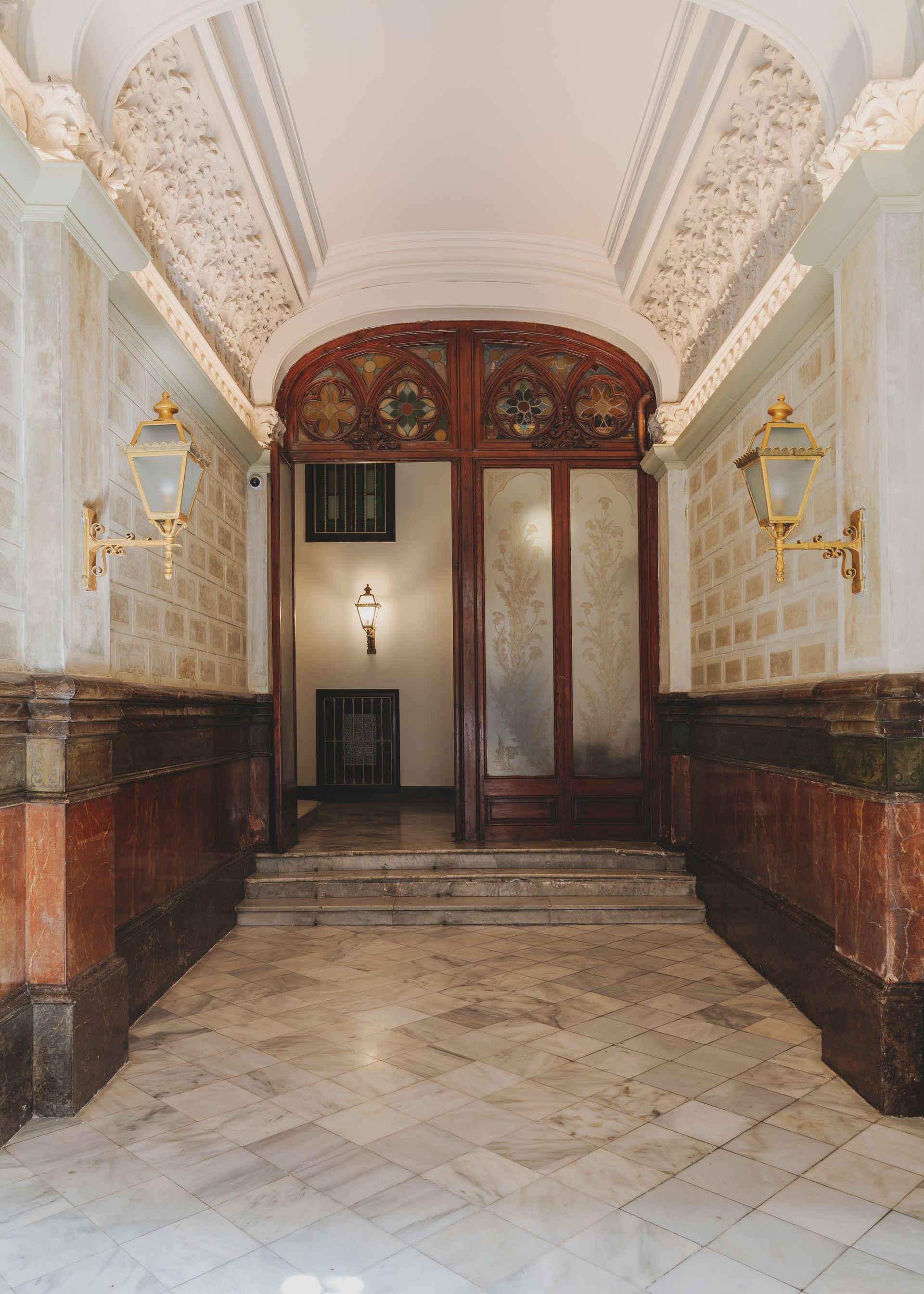 A hallway with a wooden door and stairs in a building.