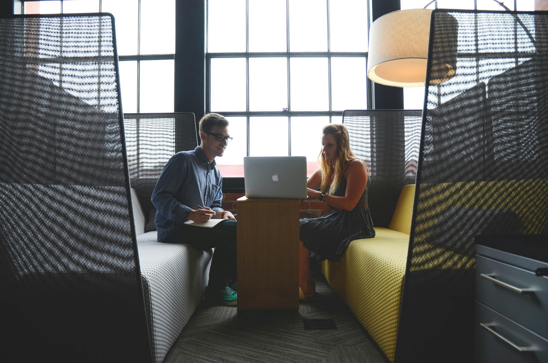 A man and a woman are sitting at a table with a laptop.