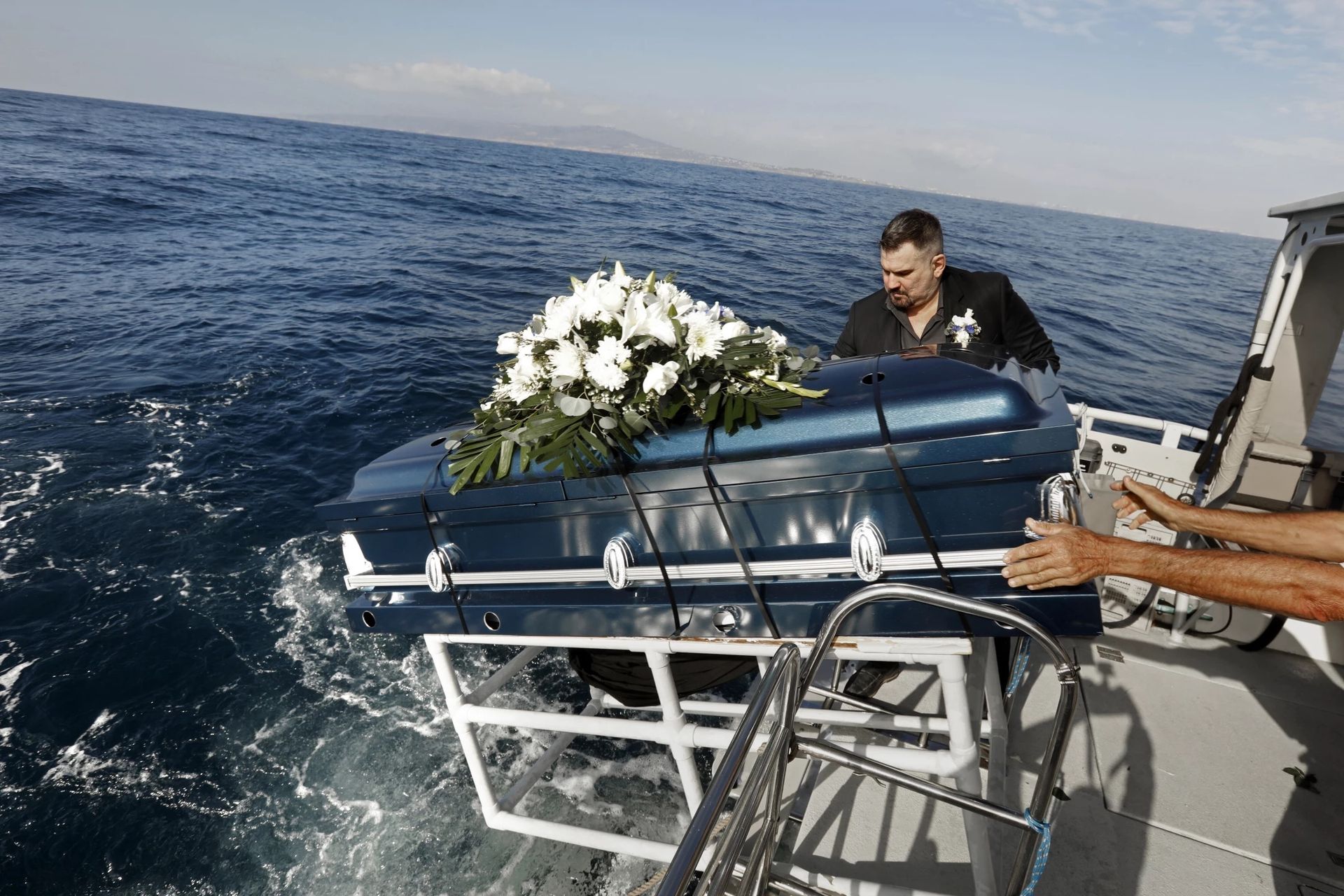 Funeral director Ken McKenzie lowers the casket of a friend, Joyce Faye Gordan, into the sea. It was her wish to be buried this way. (Carolyn Cole / Los Angeles Times)