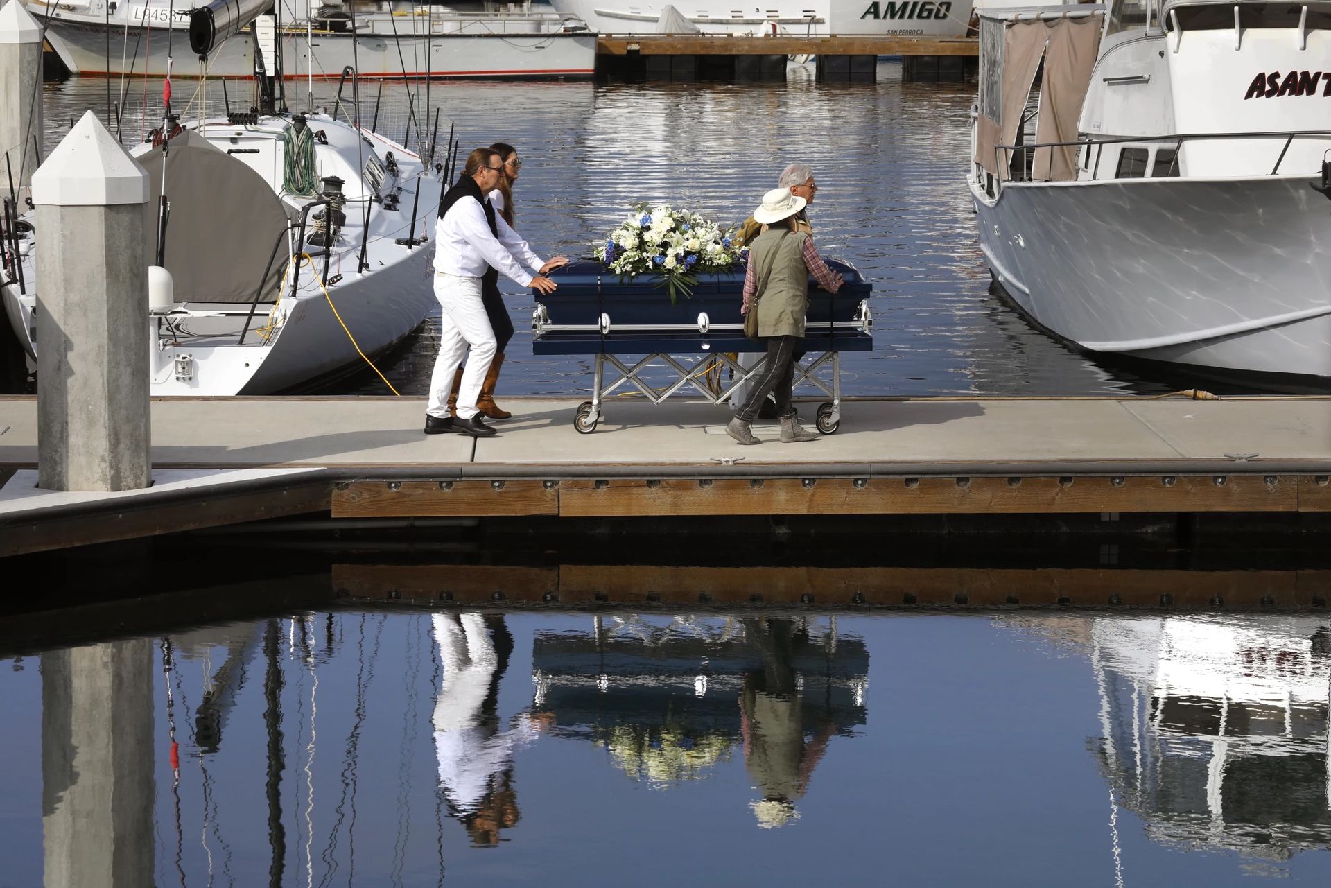 Diane Berol, at right in white hat, helps transport the casket of her husband, John, to the boat that will take him to his burial site at sea.(Carolyn Cole / Los Angeles Times)