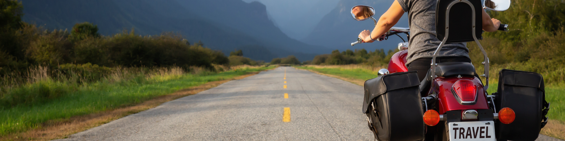 Cyclist riding on a road with mountains in the distance and a yellow center line
