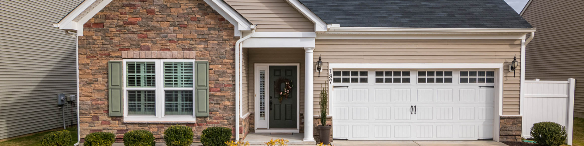 Brick single-story house with white trim, front porch, and two-car garage