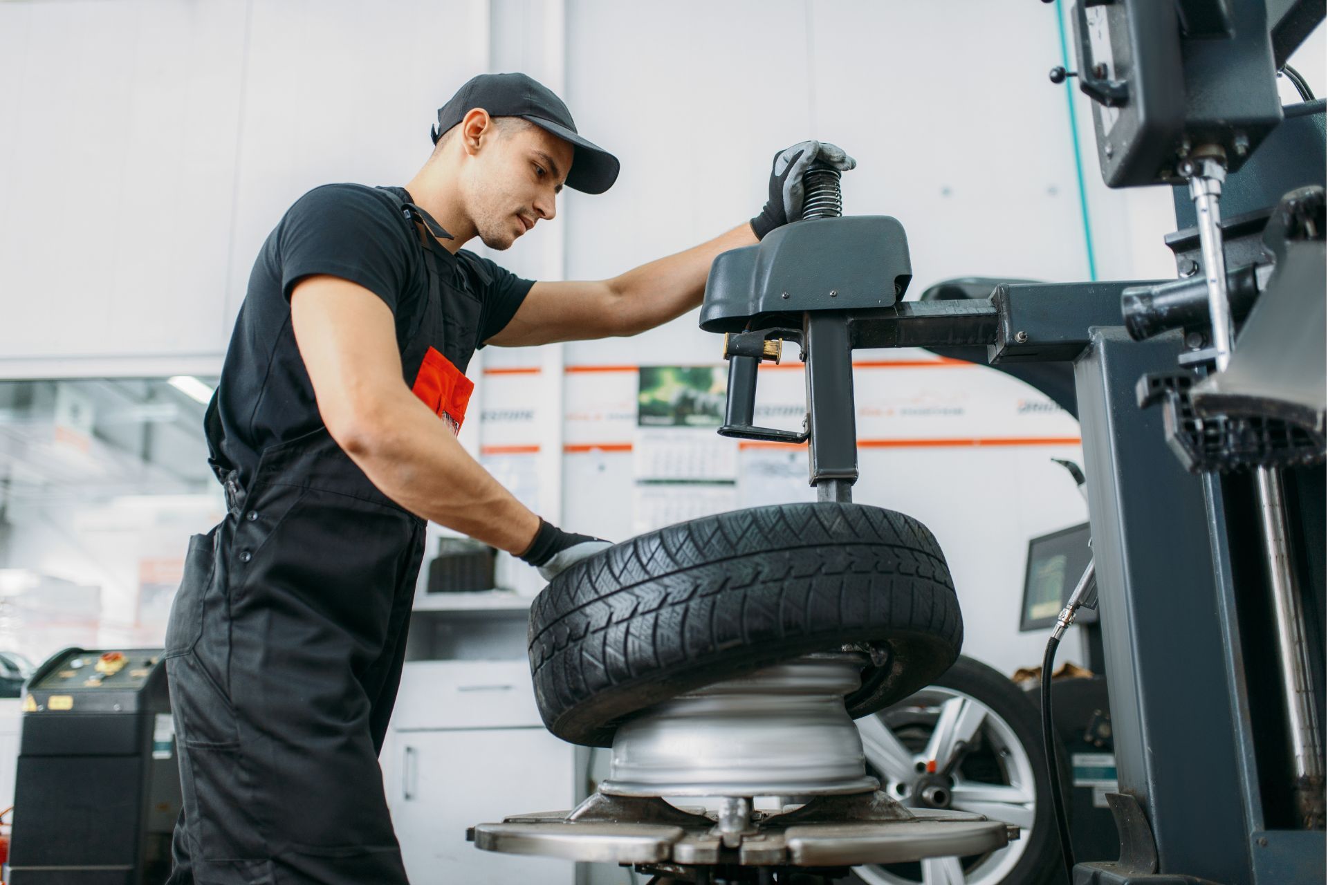 A man is changing a tire on a machine in a garage.