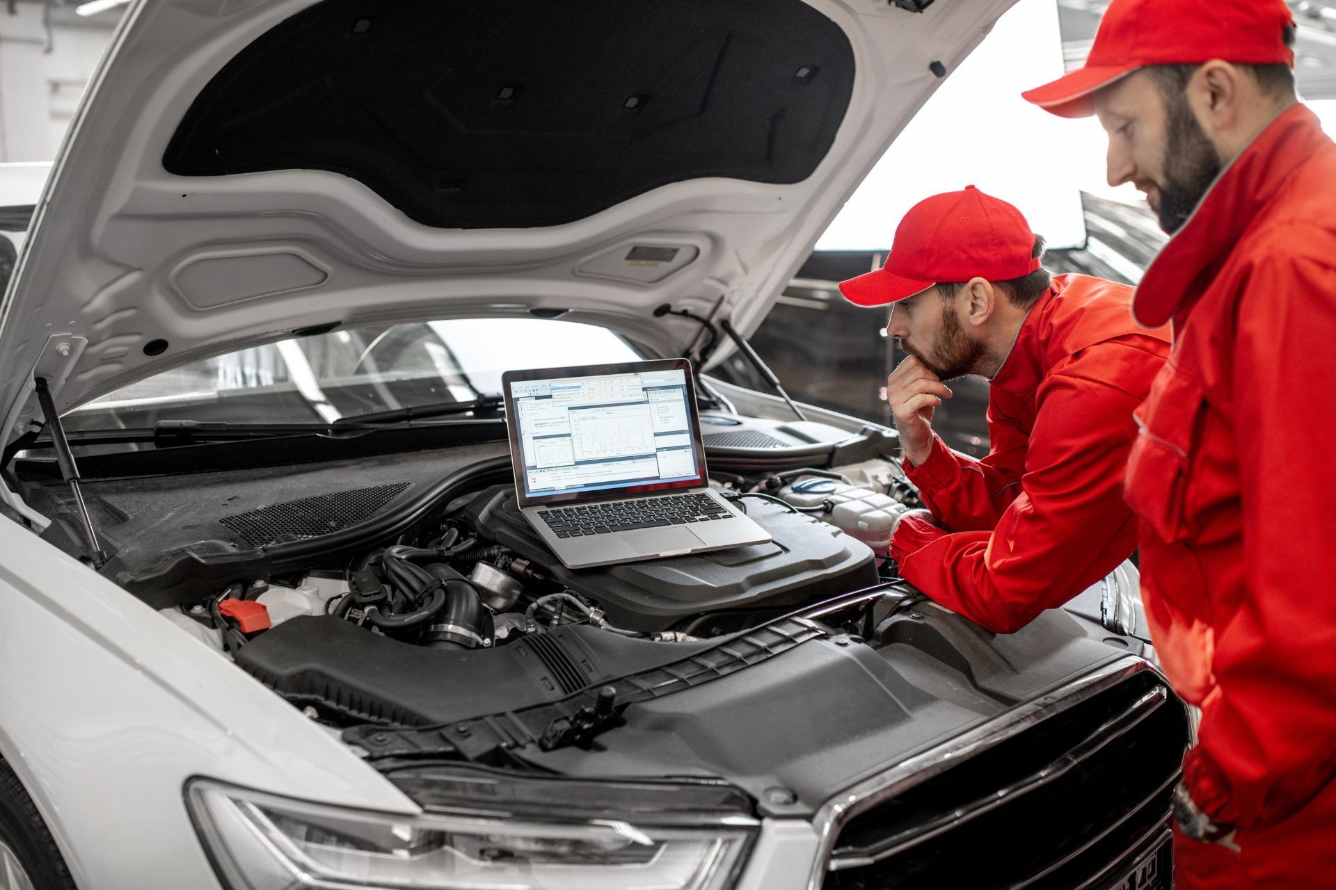 Two mechanics are working on a car in a garage.