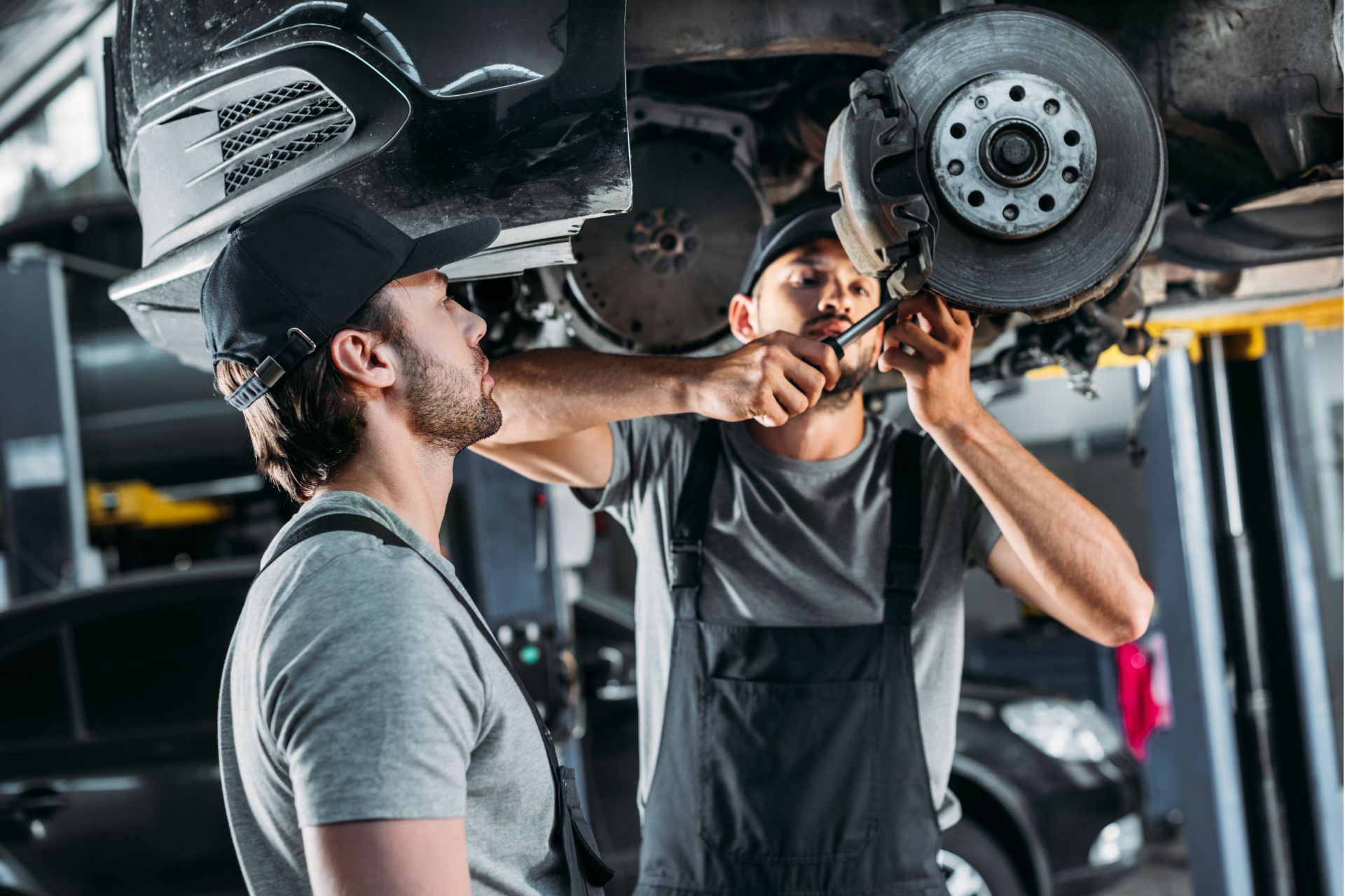 Two mechanics are working on a car in a garage.
