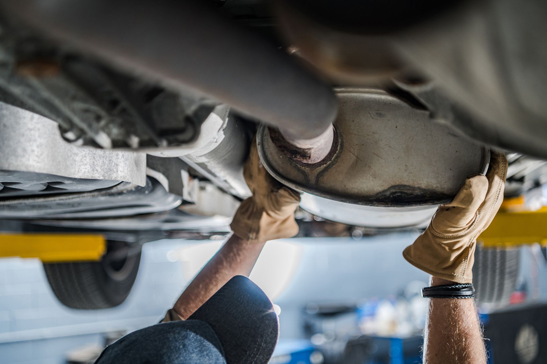 A man is working on the underside of a car in a garage.