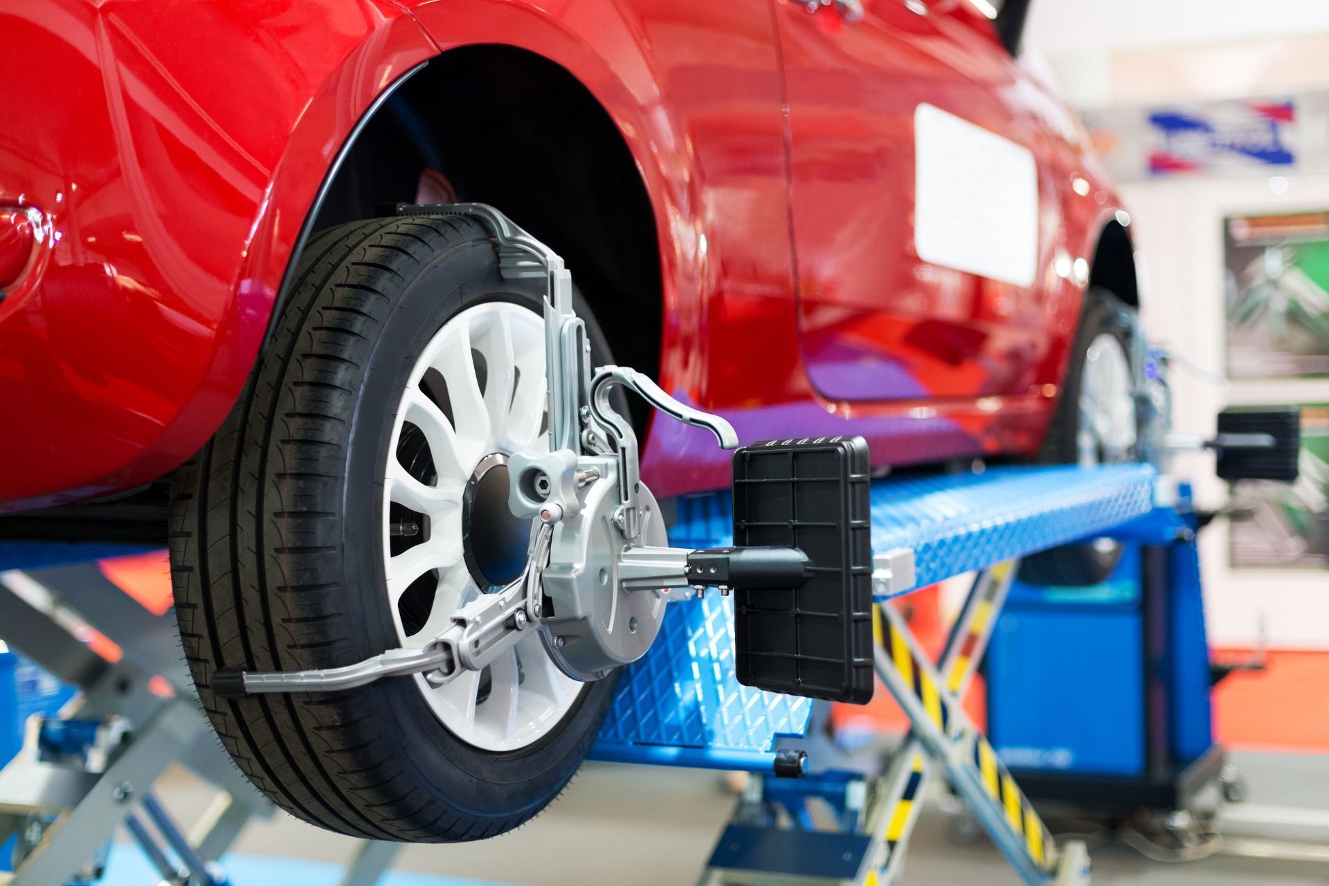 A red car is being balanced on a lift in a garage.