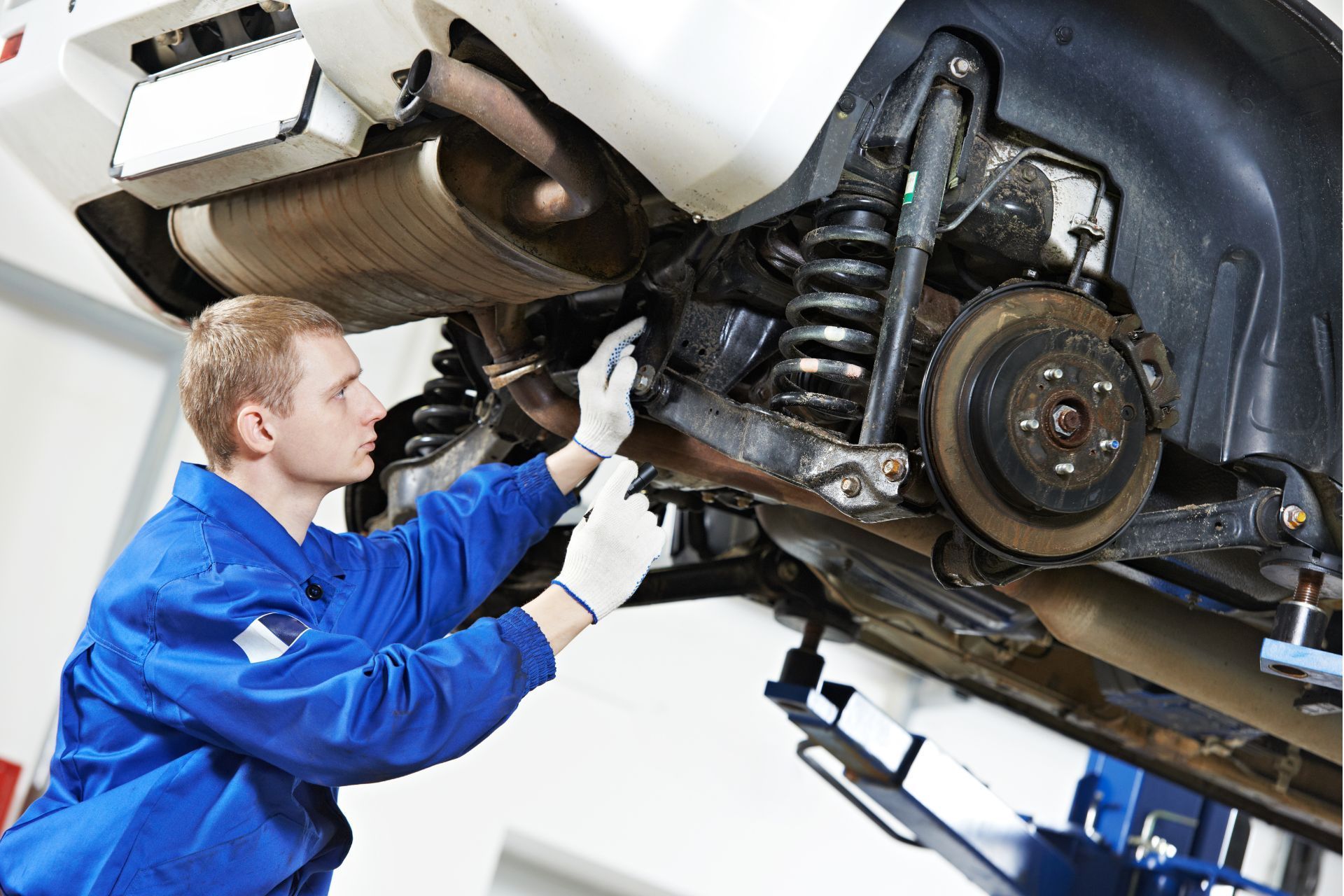 A man is working on the underside of a car in a garage.