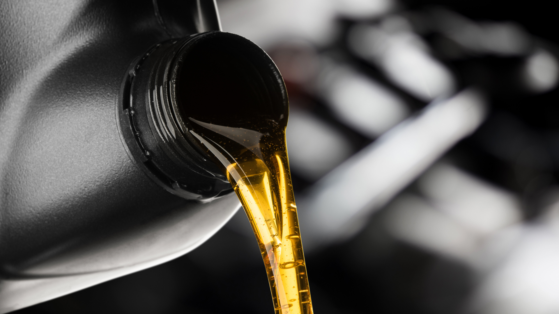 A bottle of oil is being poured into a car engine.