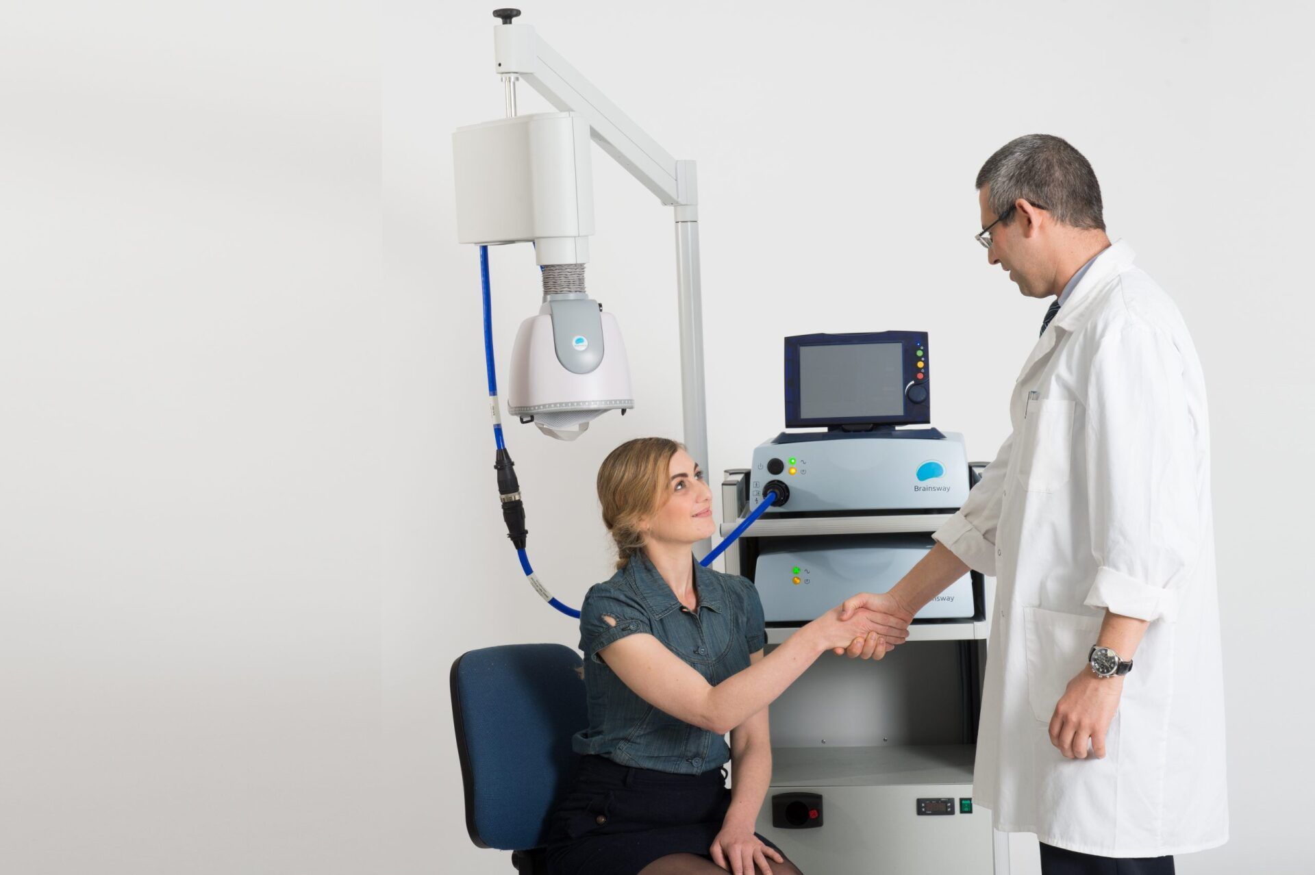 A doctor is shaking hands with a patient in front of a machine.