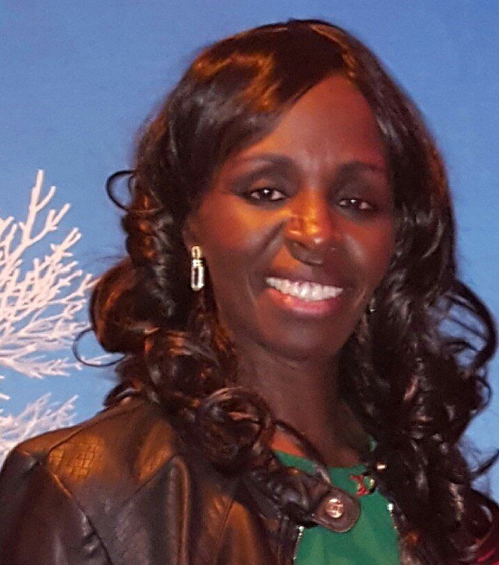 A woman wearing earrings and a leather jacket smiles for the camera