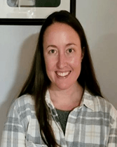 A woman in a plaid shirt is smiling for the camera.