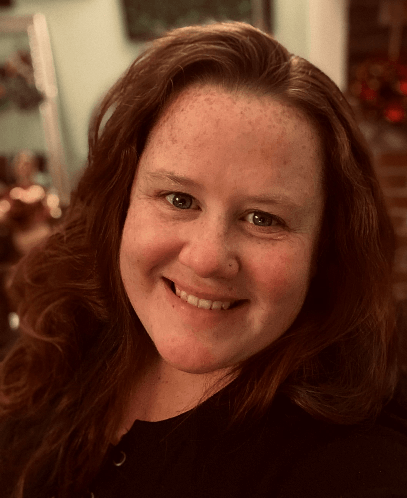 A woman with red hair and freckles is smiling for the camera.