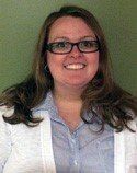 A woman wearing glasses and a white jacket is smiling for the camera.