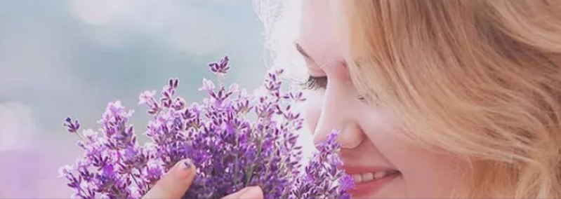 A woman is smelling a bunch of purple flowers.