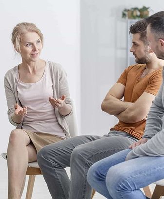 A woman is sitting in a chair talking to two men