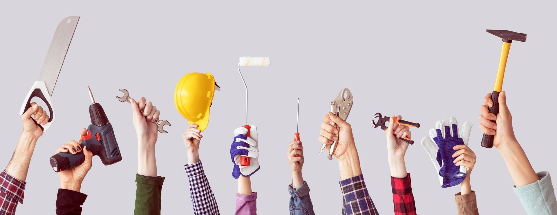 mehrere Hände halten Werkzeuge in die Höhe
