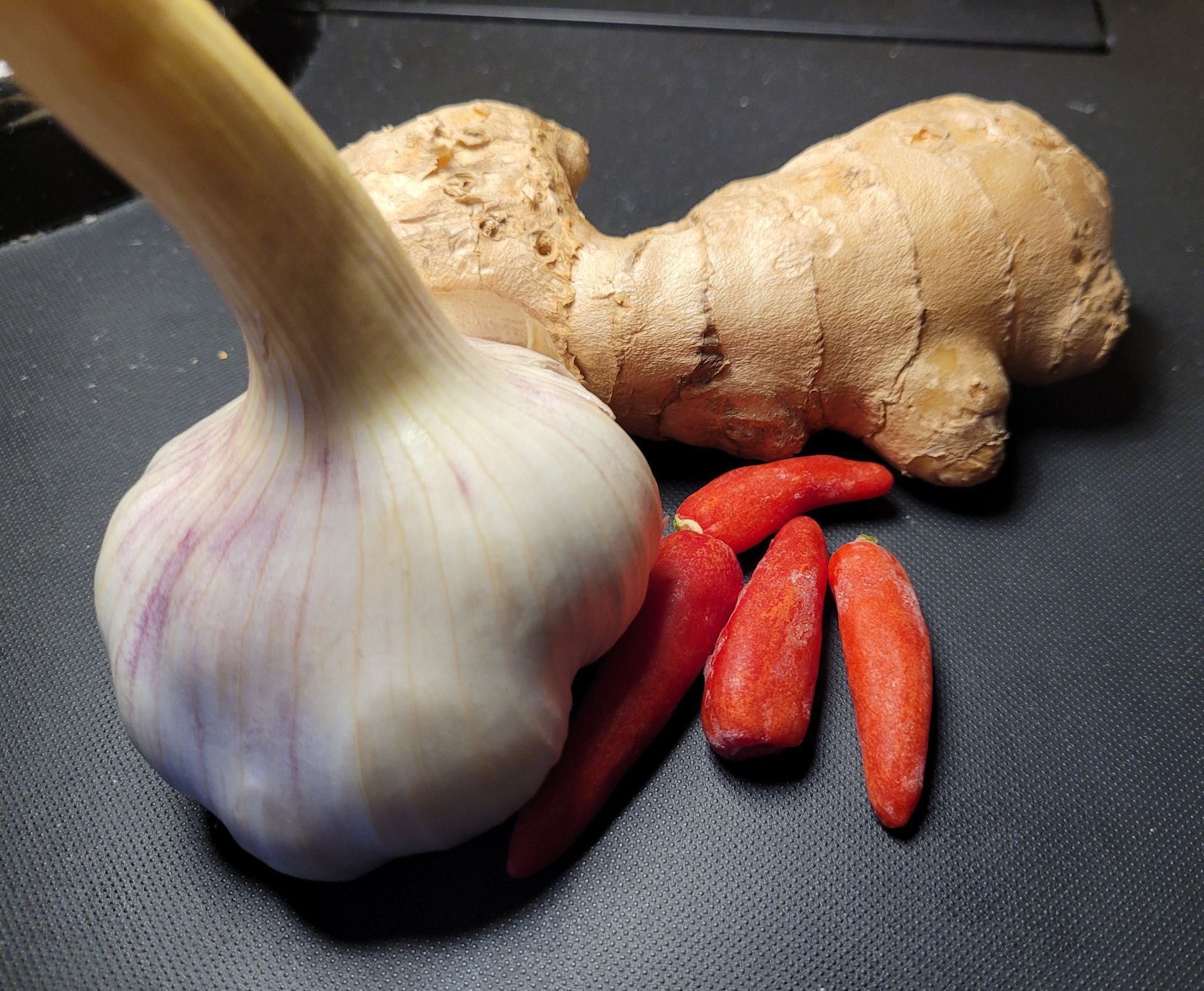 Knoflook, gember en rode pepers op een zwart oppervlak