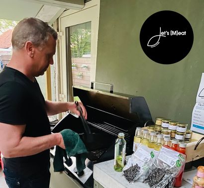 Een man in een zwart shirt staat voor een grill