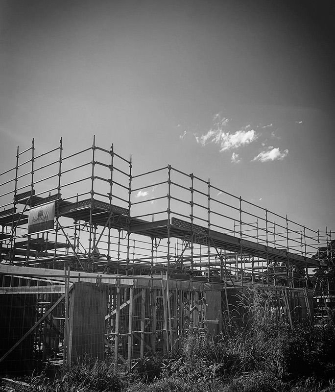 A Black and White Photo of a Building Under Construction With Scaffolding — RM Scaffolding Solutions in Kingscliff, NSW