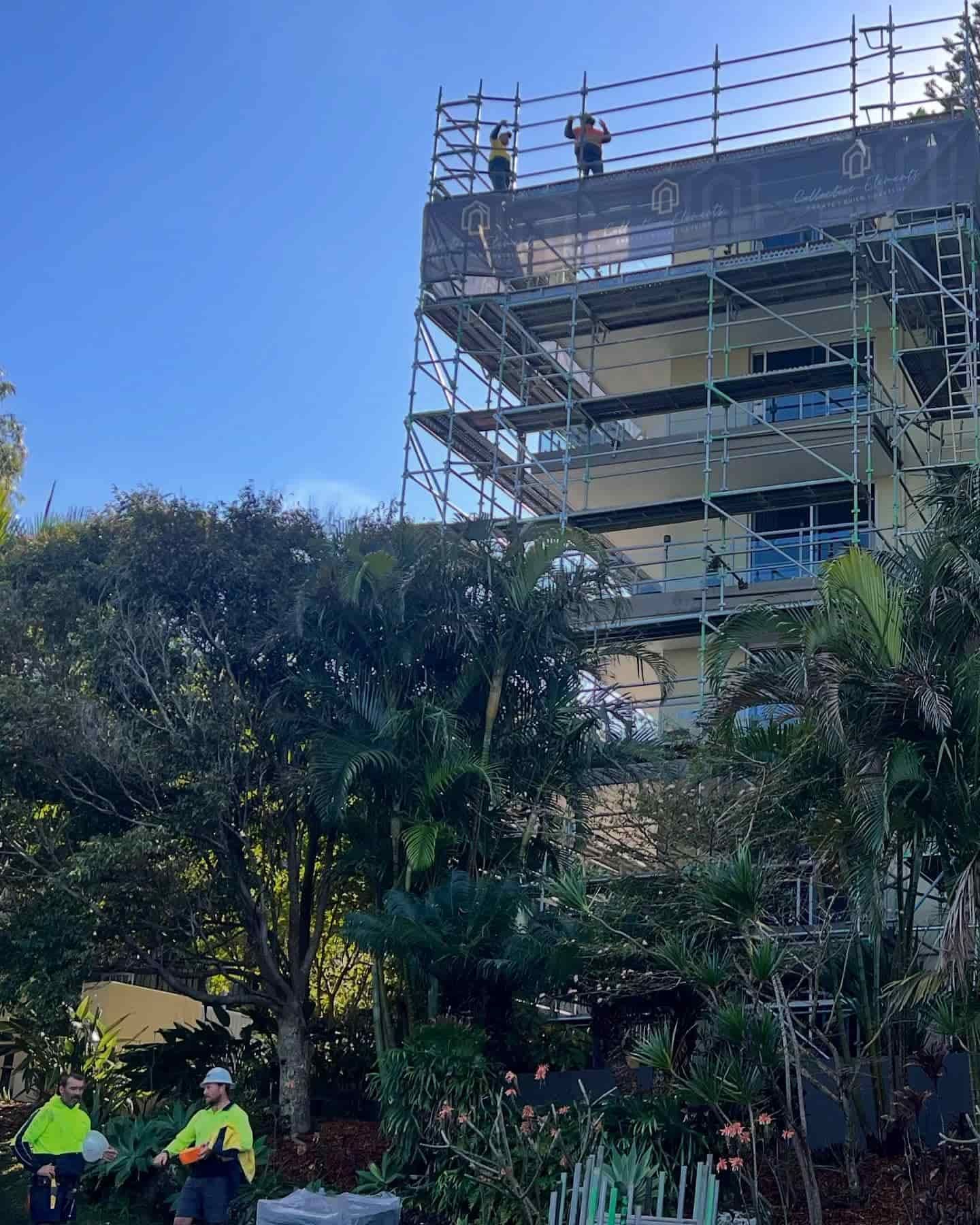 A Group of Construction Workers Are Working on the Roof of a Building — RM Scaffolding Solutions in Lennox Head, NSW