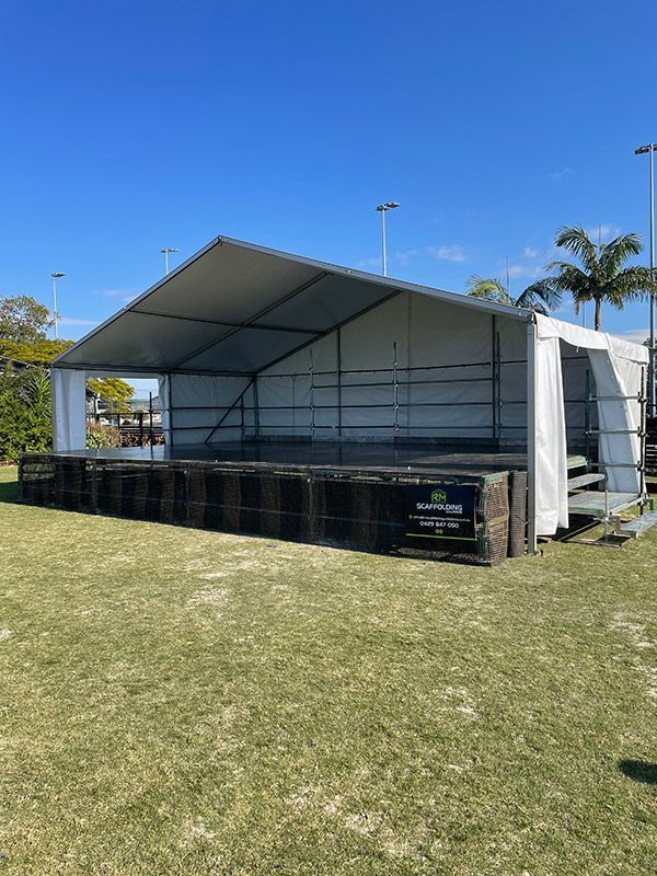 A Large White Tent is Sitting on Top of a Lush Green Field — RM Scaffolding Solutions in Lennox Head, NSW
